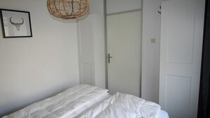 Ein Schlafzimmer mit einem Bett, einer Tür und einem gerahmten Schädelbild.