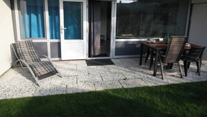 Eine Terrasse mit Stuhl, Tisch und einer Schiebetür.