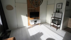 Ein modernes Wohnzimmer mit Flachbildfernseher, Holzschrank und einer kleinen Regal-Einheit.