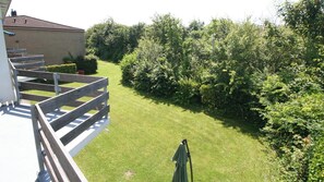 Il s’agit d’une propriété résidentielle dotée d’une pelouse bien entretenue, d’une terrasse en bois et d’une végétation dense.