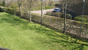 A well-maintained grassy area with trees and a parking lot in the background.