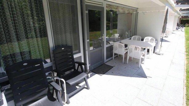 Un patio con mesa y sillas, una puerta corrediza de vidrio y vistas al jardín.