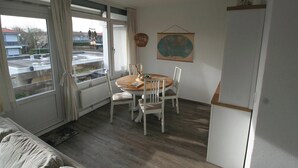 A dining area with a round table, white chairs, a view through a glass door, and a world map on the wall. - 2 bedroom accommodation in Westkapelle (Westkapelle)