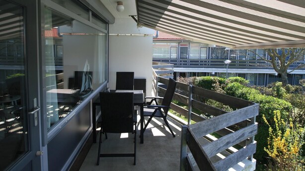 A balcony with a table and chairs, a view of buildings, and a tree. - 2 bedroom accommodation in Westkapelle (Westkapelle)