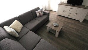 A modern living room with a grey sofa, a small wooden coffee table, and a white cabinet with a flat-screen TV. - 3 bedroom accommodation in Westkapelle (Westkapelle)