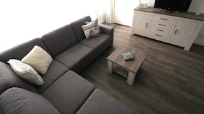 A living room with a grey sofa, a small wooden coffee table, and a white cabinet with drawers.