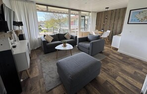 Una sala moderna con un sofá, dos sillones, una mesa de centro y un televisor.