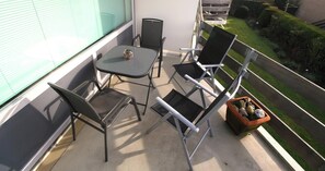 A balcony with a table and four chairs, a potted plant, and a view of a road and greenery. - 2 bedroom accommodation in Westkapelle (Westkapelle)