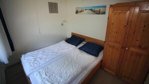 A single bed with a wooden headboard, a wooden wardrobe, and two wall-mounted pictures. - 2 bedroom accommodation in Westkapelle (Westkapelle)