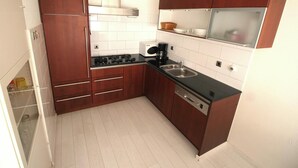 Eine kompakte Küche mit Holzausstattung, einer eingebauten Mikrowelle, einer Kaffeemaschine und einem Geschirrspüler.