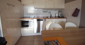 A compact kitchen with a dishwasher, oven, and a coffee maker.