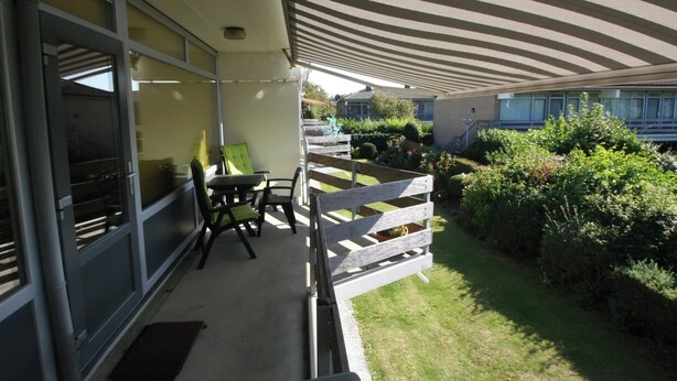 Ein Balkon mit Blick auf einen Garten, inklusive Tisch und Stühlen.