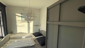 Ein Schlafzimmer mit einem Etagenbett, einem Nachttisch, einer Hängeleuchte und einem Fenster mit Vorhängen.