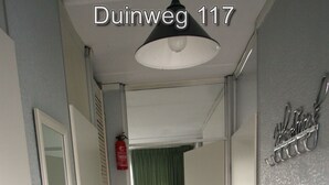 Ein Flur mit einem Feuerlöscher, einem grünen Vorhang und einem Schild an der Wand.