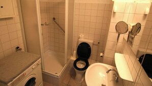 Ein Badezimmer mit Dusche, Toilette, Waschbecken und Spiegel.