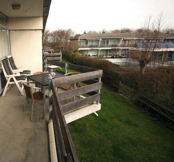 A balcony with outdoor seating, a table, and a view of a residential building. - 3 bedroom accommodation in Westkapelle (Westkapelle)