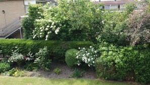 Un jardin agrémenté de divers arbustes et de plantes à fleurs, un mur en briques et un escalier.