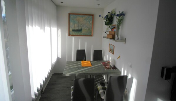 Ein Essbereich mit Tisch, Stühlen, einem Gemälde und einer Regal mit Blumen.