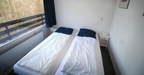 Une chambre avec deux lits, une fenĂȘtre donnant sur un beau paysage, une table de chevet et un radiateur.