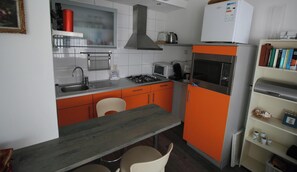 Une cuisine compacte équipée d’une cuisinière à gaz, d’un four à micro-ondes et d’un petit réfrigérateur.