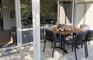 Ein Essbereich im Freien mit einem Tisch für zwei Personen, komplett mit einer Weinflasche, einem Glas und einer Käseplatte.