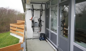 Ein Balkon mit Fahrrädern, einem kleinen Hocker und einer Tasche.
