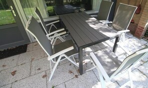Ein Patio-Tisch mit vier Stühlen, eine Glastür und eine Ziegelwand.