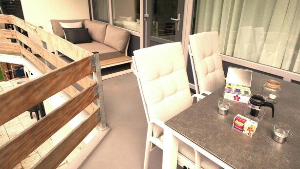 Un balcon avec une balustrade en bois, un canapé et une table avec des chaises, ainsi qu'une boîte de mouchoirs.