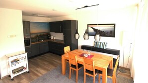 Une cuisine moderne avec des meubles de couleur sombre, une table à manger avec des chaises et un tableau accroché au mur.