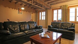 A living room with two black leather sofas, a wooden coffee table, and a ceiling with exposed wooden beams. - Charming authentic Norman house with fireplace and pets allowed (Barenton)