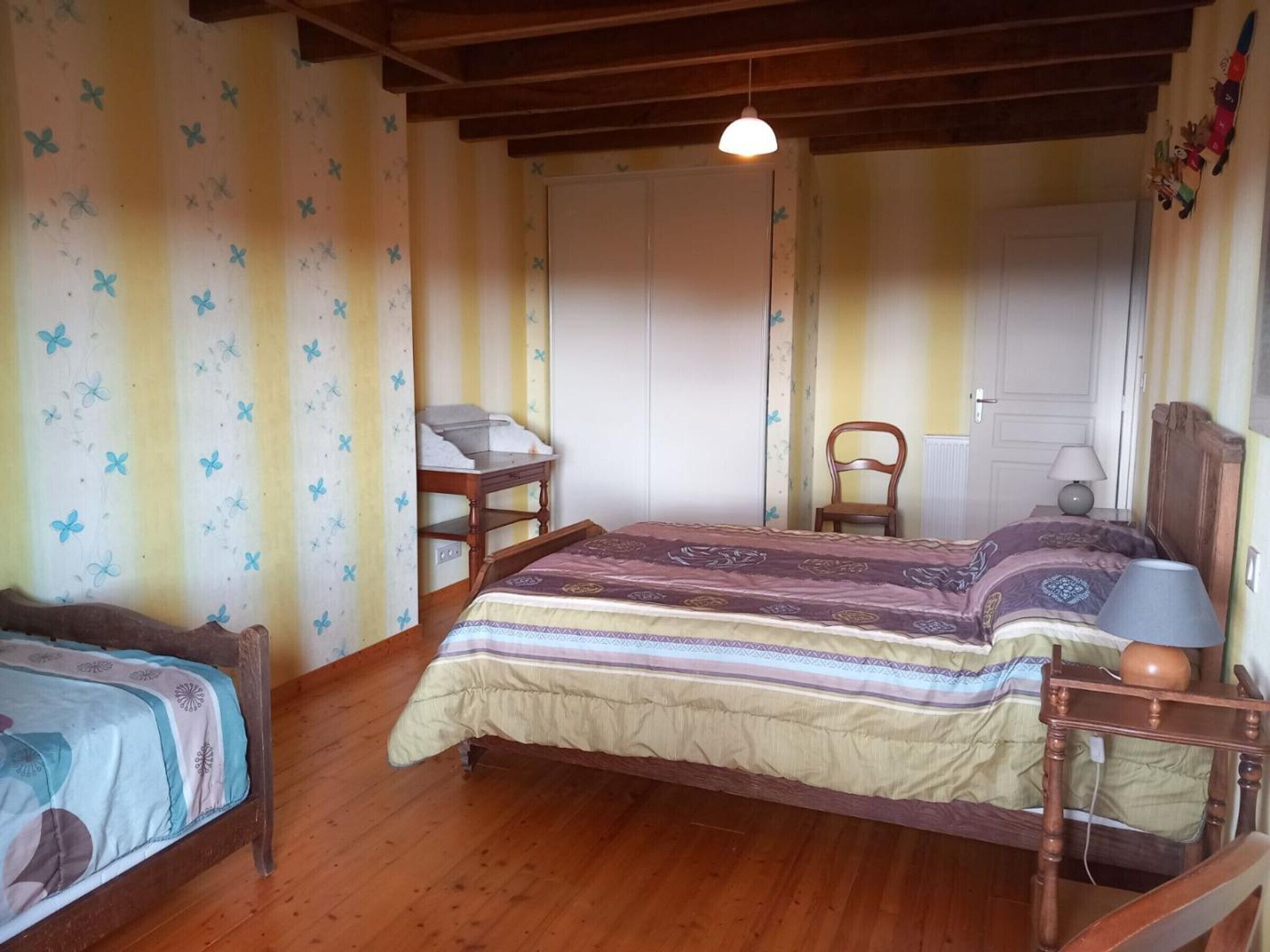 Un dormitorio con una cama de madera, un escritorio, una silla y un armario.