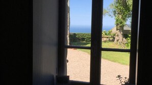 A room with a large window overlooking a garden and a view of the sea. - Cozy house with garden, pets allowed, WiFi in La Hague (La Hague)