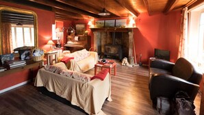 A cozy room with a wooden ceiling, a fireplace, a piano, a sofa, and a television. - Cozy house with garden, pets allowed, WiFi in La Hague (La Hague)