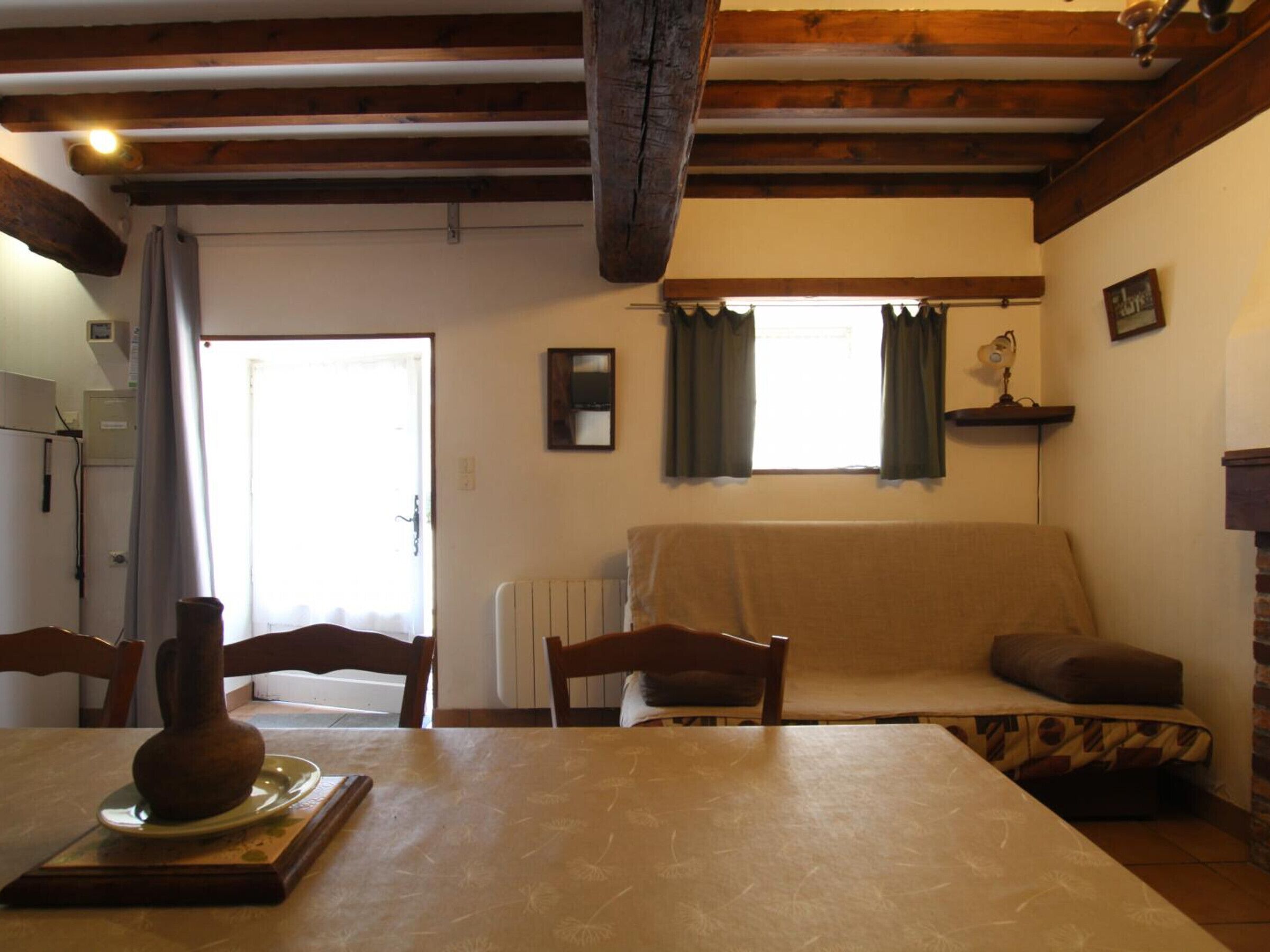 Una sala acogedora con un sofá, una mesa con un jarrón y una ventana con cortinas.