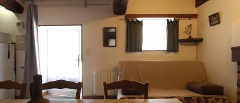 Una sala acogedora con un sofá, una mesa con un jarrón y una ventana con cortinas.