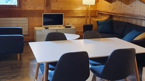 A cozy cabin-style room with a wooden interior, a white desk with a computer, a sofa, and a lamp.