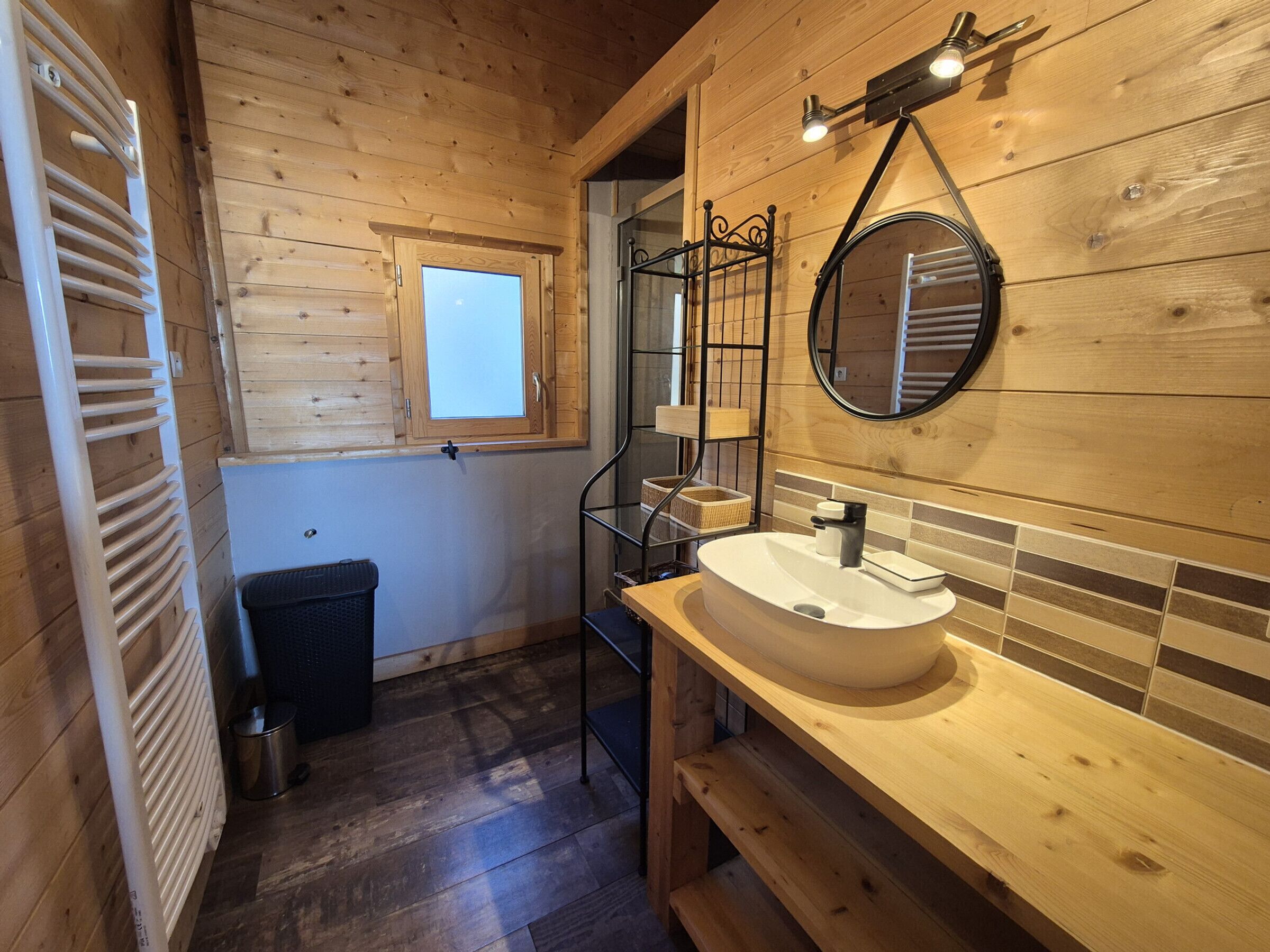 Un interior de madera con un banco, un lavamanos con espejo y una ventana.