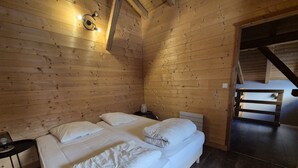 A wooden room with two beds, a small table, and a staircase.