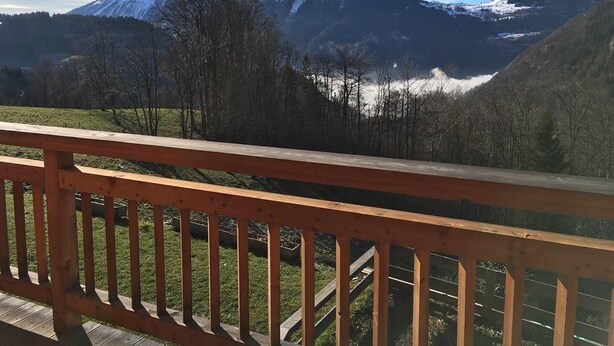 A mountain landscape with a wooden deck in the foreground.