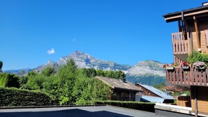 A mountain view with a wooden building featuring balconies with flower boxes.