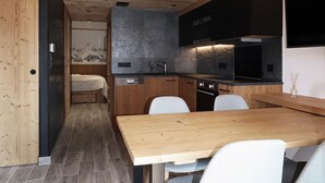 A compact kitchen with wooden cabinets, a built-in stove, and a dining area with a wooden table and chairs.