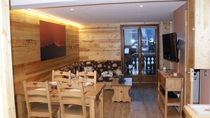 A wooden interior with a dining area, a television, and a view through a glass door. - Renovated 50 m² apartment, 2 bedrooms, central, WIFI (Les Carroz d'Arâches)