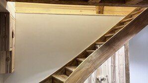 Un escalier en bois, avec un mur blanc et une porte en bois.