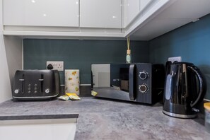 A kitchen with a toaster, a microwave, a kettle, and a decorative item on the counter.