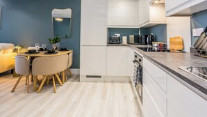 A modern kitchen with white cabinets, a dining area with a round table, and a light-colored floor. - The Sapphire at Parsons House (Washington)