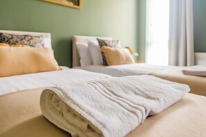 A hotel room with two beds, each with white linens and decorative pillows.