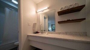 A bathroom with a white sink, a mirror, a towel rack, and a shower curtain.