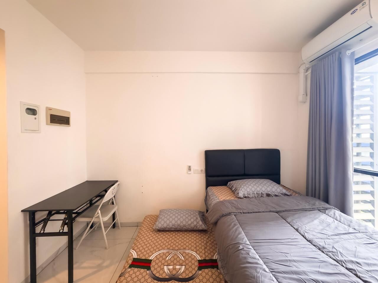 Une petite chambre à coucher, bien rangée, avec un lit, un bureau et une fenêtre avec des rideaux.