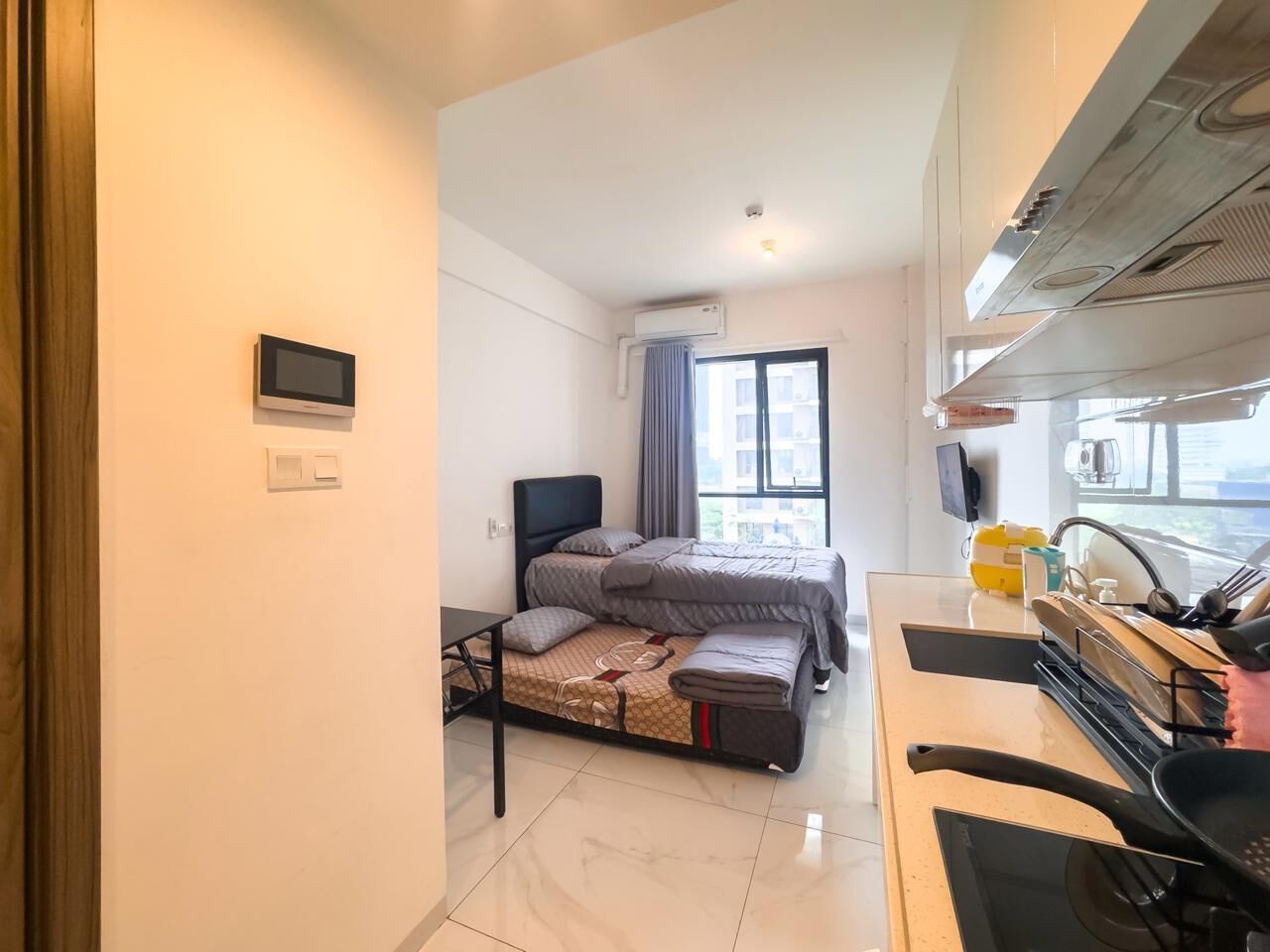 A compact bedroom with a bed, a small desk, and a window.
