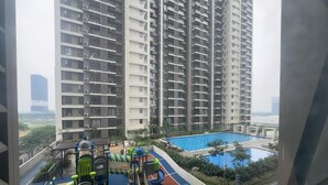 Un edificio residenziale alto con un parco giochi sul tetto e una piscina.